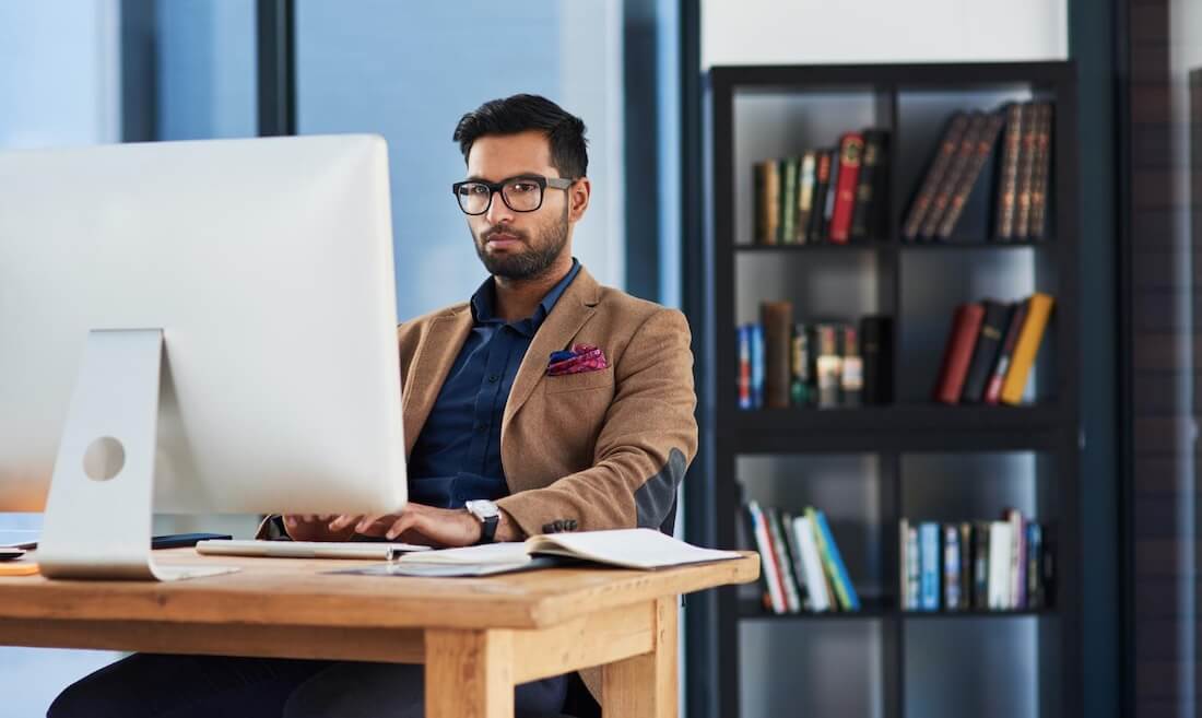 A male professional working on a computer using federated search to enable employees to access and synthesize information from multiple sources effortlessly